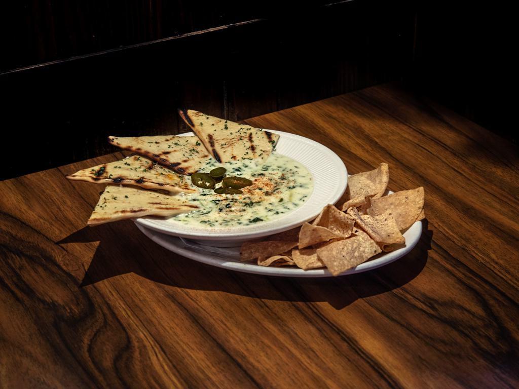 Spinach Artichoke Queso · A rich blend of creamy cheese, spinach, artichoke hearts, jalapenos and onions served with tortilla chips and warm flatbread.