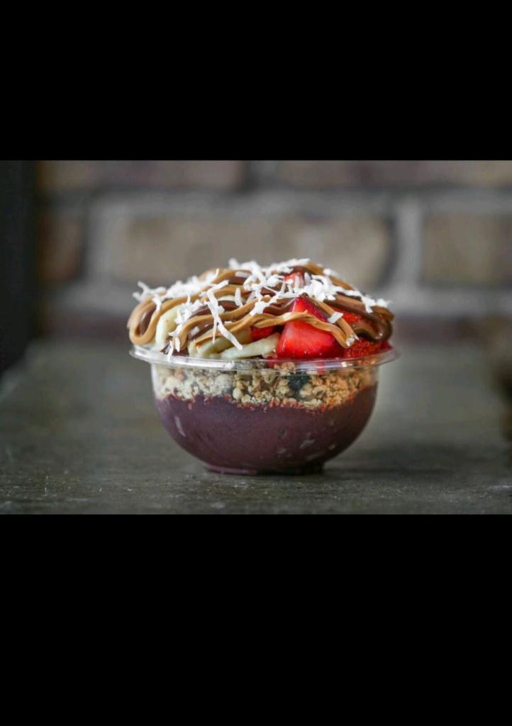 Frutella Bowl · Organic acai and banana bases topped with granola, banana, strawberries, Nutella, peanut butter and coconut flakes.