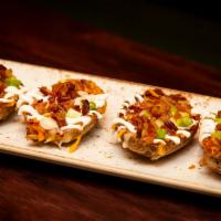 Potato Skins · Crispy potato skins filled with cheddar cheese, caramelized bacon, scallions, and sour cream.
