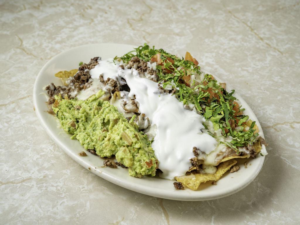 Nachos · Tortilla chips topped with guacamole, tomato, sour cream, cheese, beans and your choice of mozzarella or cheese dip.