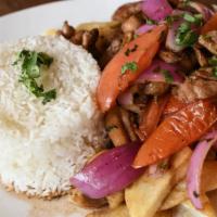 Pollo Saltado · Stir fry chicken, red and green onions, tomato, parsley, over rice and fries.