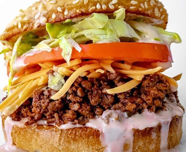 Taco on a Bun · No taco shell, All else is on a sesame seed bun. Freshly cooked ground beef, cut tomatoes, shredded cheese and lettuce with our house special sauce!