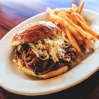 Pulled Pork Sandwich · Oscar’s pulled pork tossed with BBQ sauce and piled high on a brioche bun, topped with cole ...