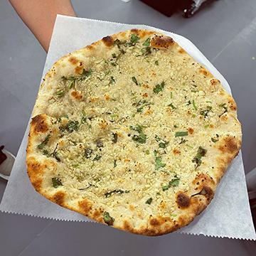 Garlic Naan · Step your Naan game up!
Naan Bread topped with Fresh Garlic, Cilantro and finished off with butter.