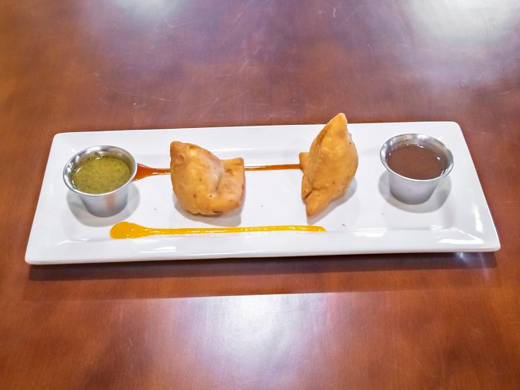 Samosa · Hand made pastry stuffed with potatoes, green peas and spices, deep fried and served with tamarind sauce.