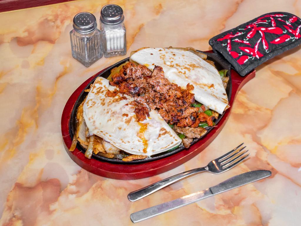 Fajitas Montes · Steak, chicken, shrimp, chorizo and 2 quesadillas on top and cheese dip on top and red sauces on top.