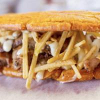 Patacon Pernil · Green plantain, shredded pork, Guayanes cheese, homemade sauce and potato sticks. Fried gree...
