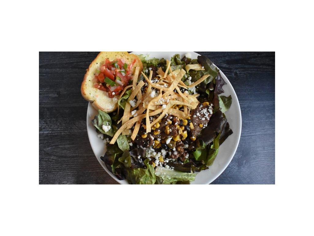 Santa Fe Salad · A bed of fresh salad greens layered with steak, fire roasted vegetables, tortilla strips, tomatoes and our house made avocado dressing