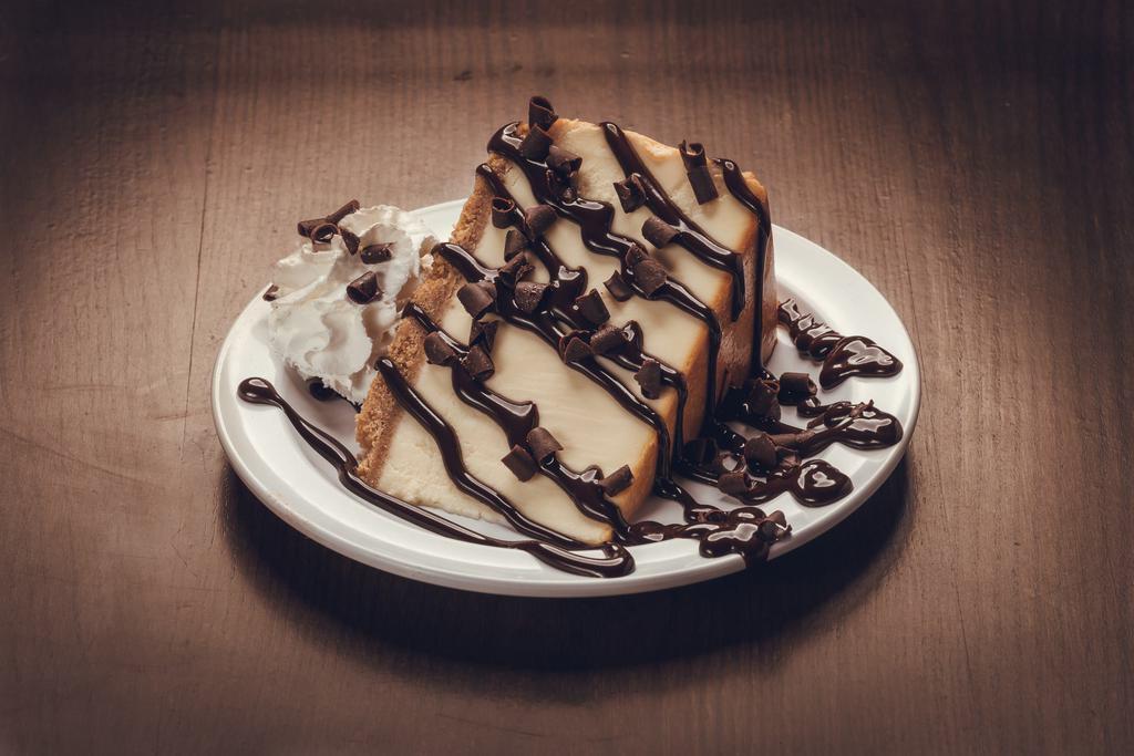 Chocolate Cheesecake · A colossal slice of New York cheesecake topped w/ chocolate sauce, shaved chocolate and whipped cream. 