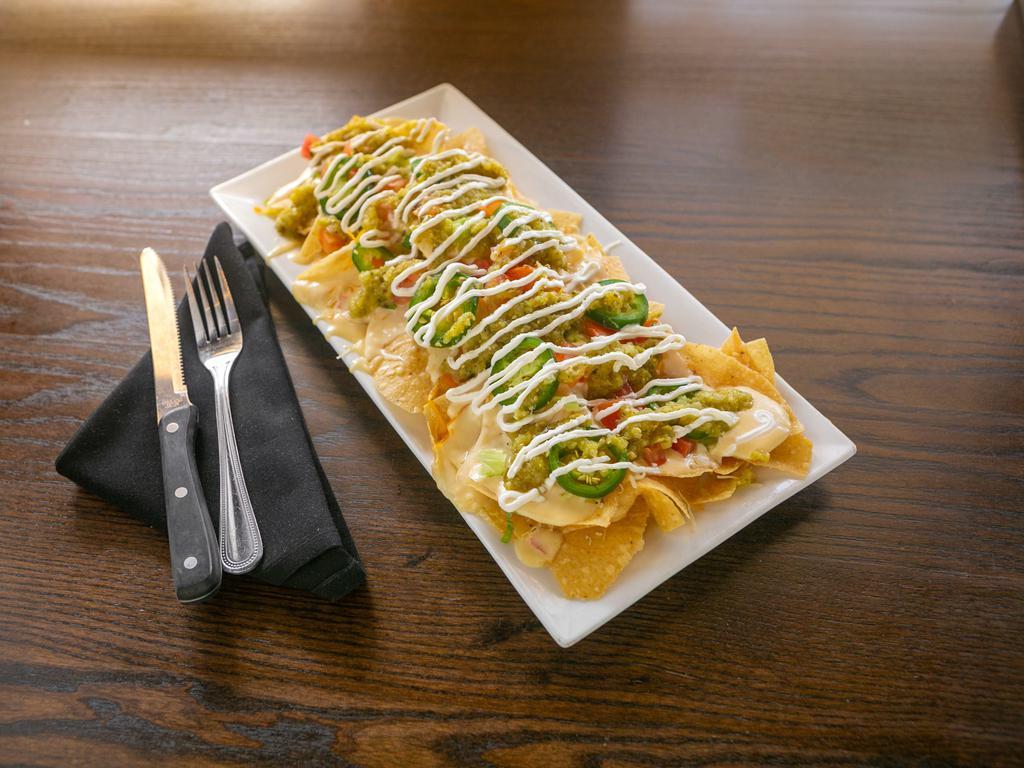 Nachos · Spicy! Crisp tortilla chips topped with cheddar, tomato, scallion, fresh jalapeno, queso, sour cream and house-made salsa verde. Vegetarian, gluten-free.