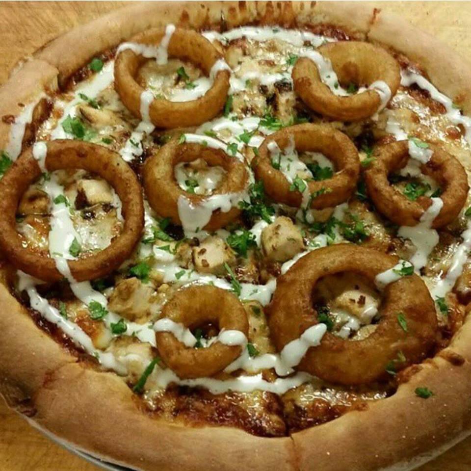 Rodeo Pizza · BBQ base topped with mozzarella cheese, chicken, bacon, fresh cilantro and onion rings then drizzled with ranch.