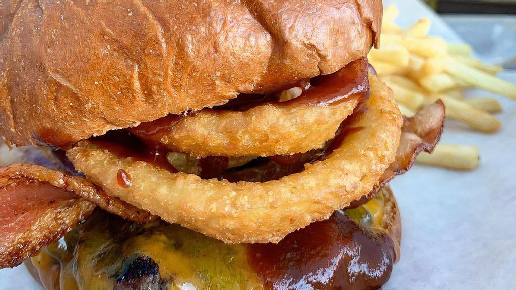 Western Burger · 1/3 LB Angus beef, cheddar cheese, two strips of bacon, two crispy onion rings, tangy BBQ sauce  on a brioche bun,  served with fries 
