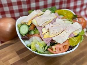 Chef Salad · Sliced turkey breast, ham, provolone, and American cheese on top of crisp lettuce, sliced red ripe tomatoes, onions, cucumbers, olives, and pepperoncinis with your choice of dressing.