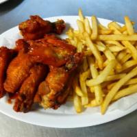 Wings · Cooked wing of a chicken coated in sauce or seasoning. Served with french fries. Servido con...