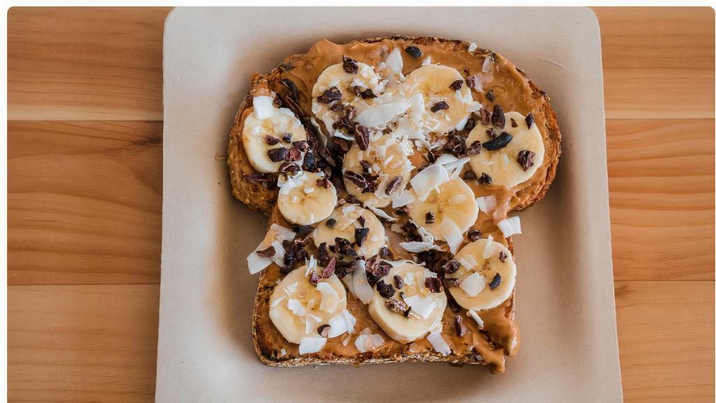 Coconut Peanut Butter · Multi Grain Toast topped with Coconut Peanut Butter, Banana, Cacao Nibs, Organic Coconut Chips, and Local Honey.
