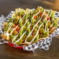 Nachos  ·  A bed of tortilla chips, stacked with Monterey Jack, shredded lettuce, onion, tomato, guaca...