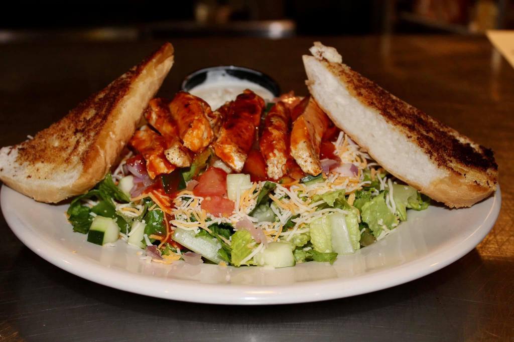 Grilled Buffalo Chicken Salad · Grilled chicken tossed in Buffalo, romaine, tomatoes, cucumber, red onion, shredded cheddar, and Jack cheese. Side of garlic bread. 