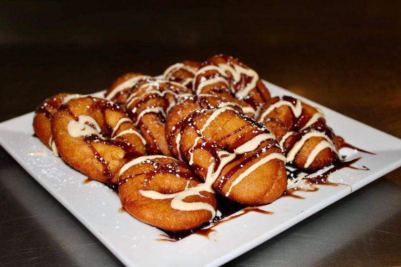 Sticky Doughnuts · 10 fried mini doughnuts, tossed in powdered sugar, drizzled in chocolate and vanilla sauce. 