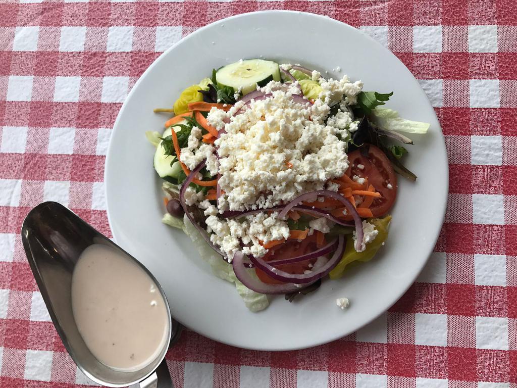 Greek Salad · Fresh lettuce blend, red onions, cucumbers, tomatoes, carrots, olives, pepperoncini peppers and feta cheese, served with our housemate Italian vinaigrette dressing. Served with our houseemade Italian garlic bread.