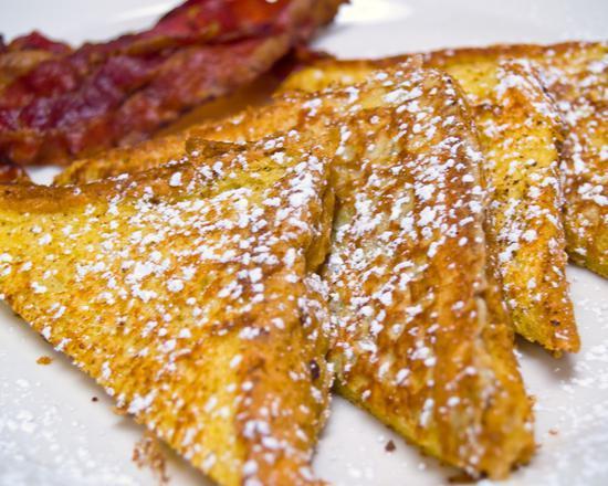 Bacon French Toast · Sliced challah bread soaked in eggs and milk, then fried and topped with crispy bacon.
