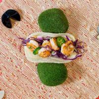 Shrimp Taco · Grilled shrimp, shredded cabbage slaw, scallions, sesame seeds, and diced onion on a torilla.