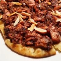 Musakhan · A Tanoreen specialty! homemade flat bread topped with sumac spiced shredded chicken, slow co...