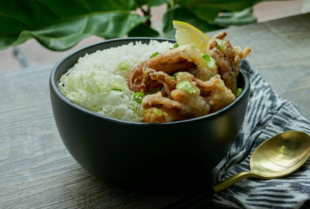 Ika Geso Donburi · Crispy breaded squid legs seasoned with salt, pepper, and lemon on top of a steaming bed of white rice and finely shredded cabbage drizzled with a yuzu-wasabi aioli, and garnished with spring onion.