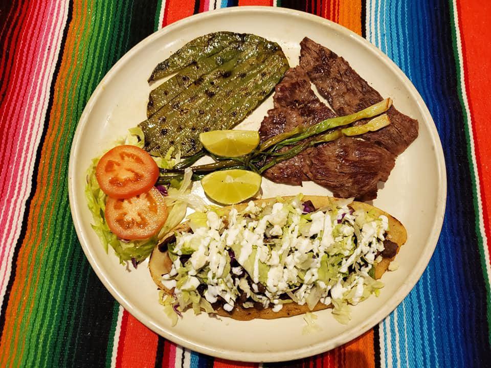 HUARACHE COMBO · A corn meal shoe shape topped with beans, meat, fresh cheese, sour cream and lettuce. A grilled cactus leave, grilled onion and a piece of grilled steak