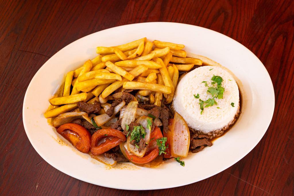 LOMO SALTADO · Peruvian Stir-Fried beef, tomatoes, red onions, soy sauce, and cilantro served with fries & white rice