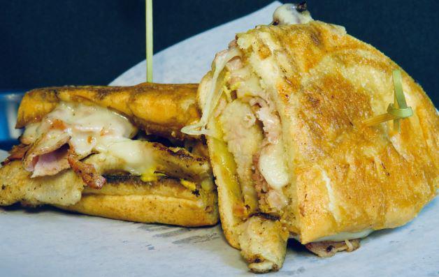 Cuban Sandwich · Pork belly brined all night and slow cooked for hours; finished with mustard, pickle, ham and melted Swiss pressed on Cuban bread.