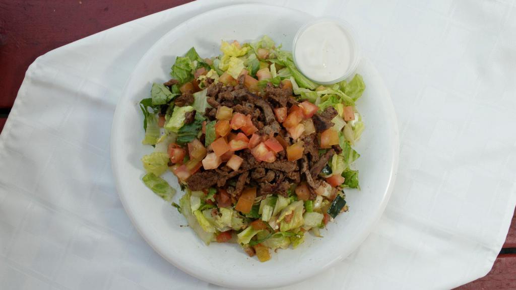 Beef Shawarma over Salad · Marinated and seasoned Beef grilled served over mixture of chopped  lettuce, tomatoes, cucumbers mixed with our house Mediterranean dressing. Comes with Tahini Sauce on the side.