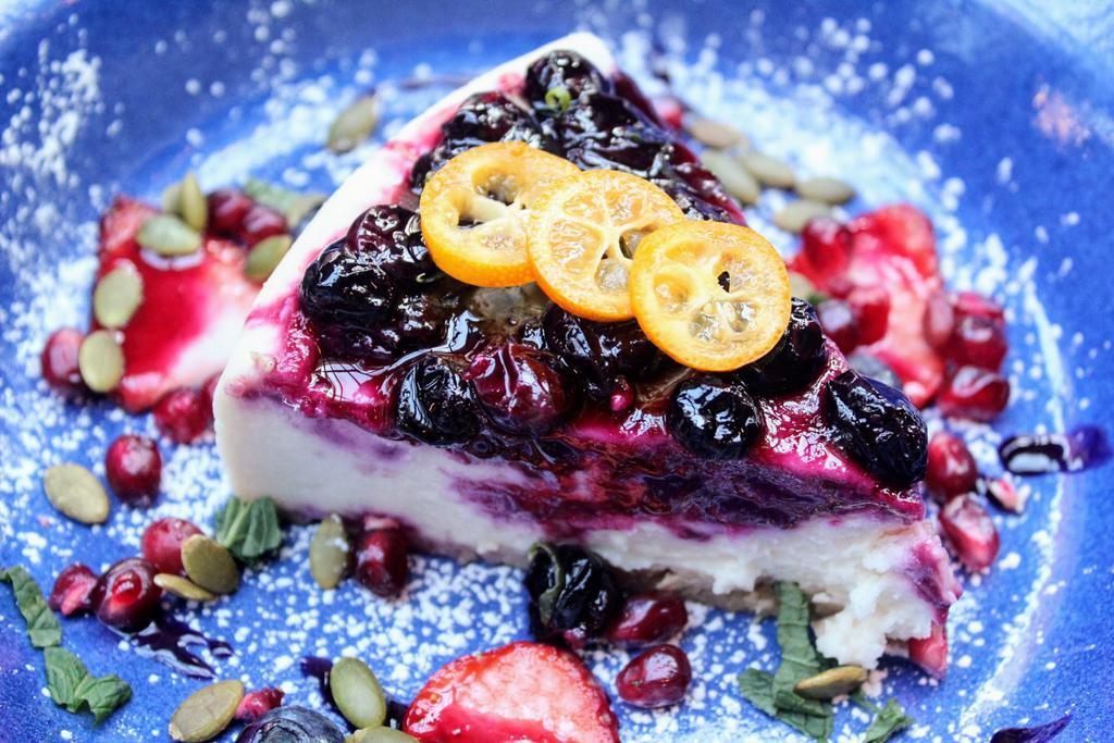 Hibiscus Berry Wine Cheesecake · Hibiscus flowers red wine reduction, blueberry lime compote, tofu coconut, graham crust, Market fruit. Contains Wheat and Soy. Nut Free.