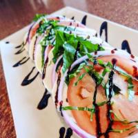 Caprese Salad · Fresh mozzarella, sliced tomatoes, basil leaves and red onion drizzled with balsamic glaze.