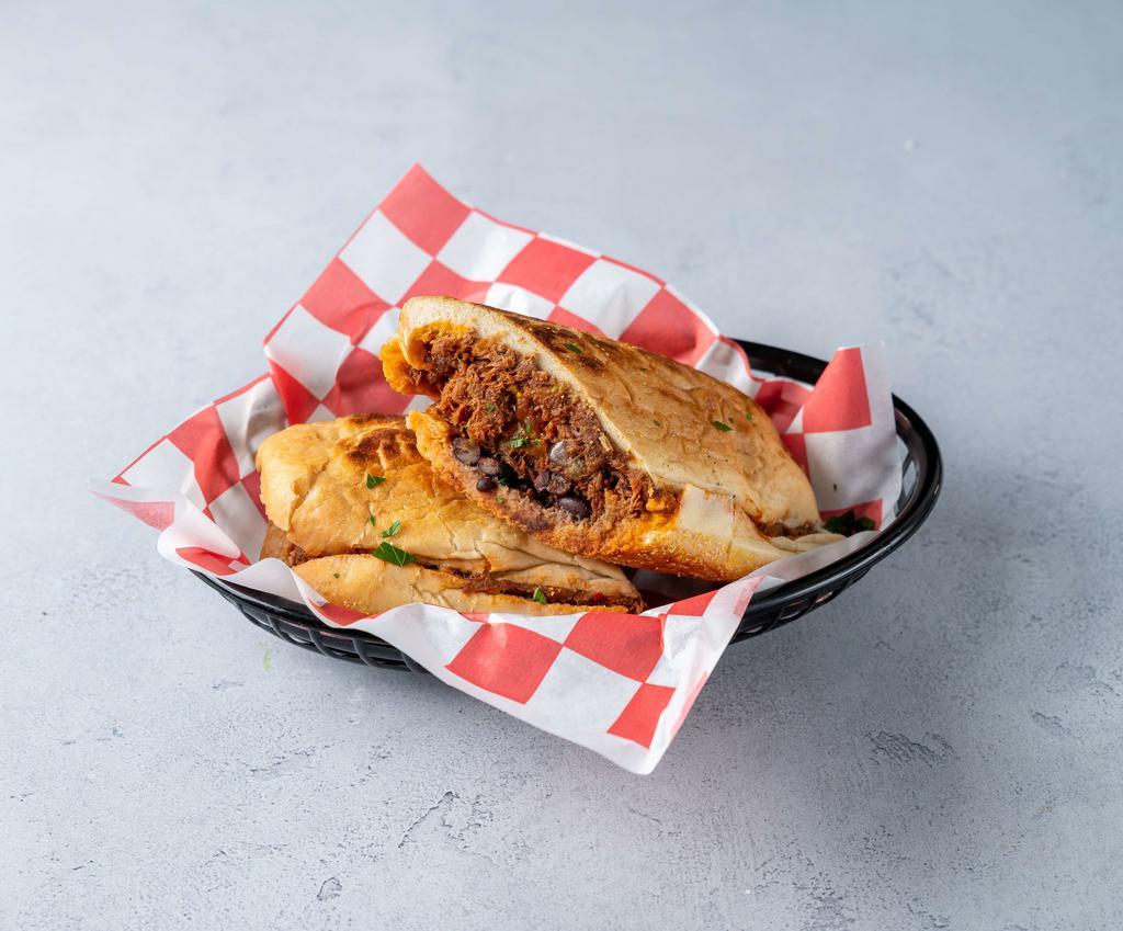 Ropa Vieja Pressed Sandwich · Slow roasted skirt steak, sweet plantains, black beans and tomato Creole sauce.  