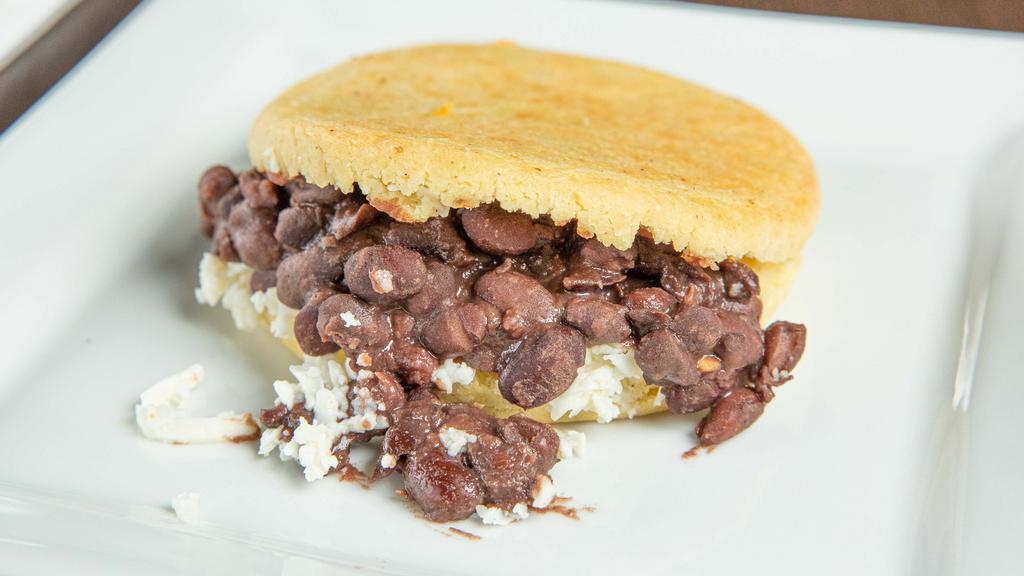 Dominó Arepa · Corn arepa filled with black beans and fresh shredded white cheese.
