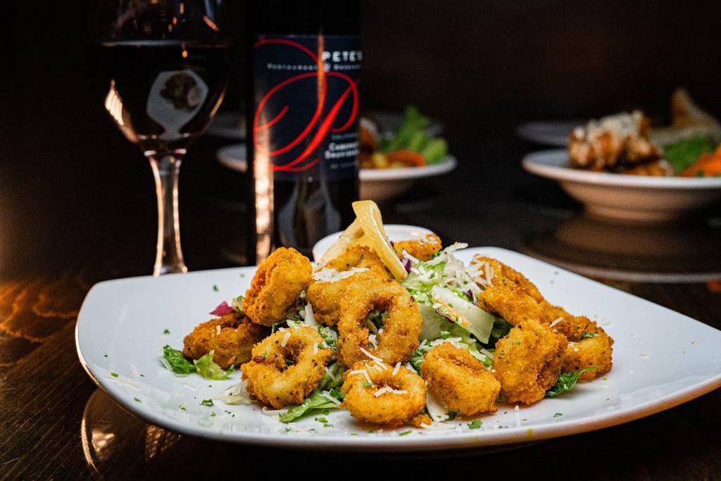 Calamari · Half-pound of freshly prepared, hand-breaded crispy calamari, fried with bell peppers & onions. Topped with Parmesan cheese, served with a side of ancho aioli.