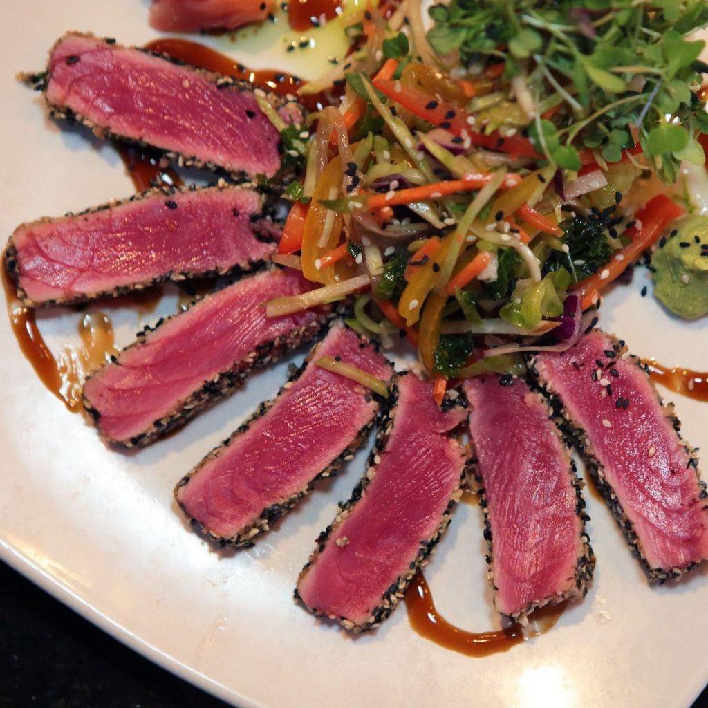 Sesame Ahi Tuna · Sesame crusted, seared rare and drizzled with Teriyaki glaze. Served with coconut jasmine rice, Asian slaw, pickled ginger and wasabi.