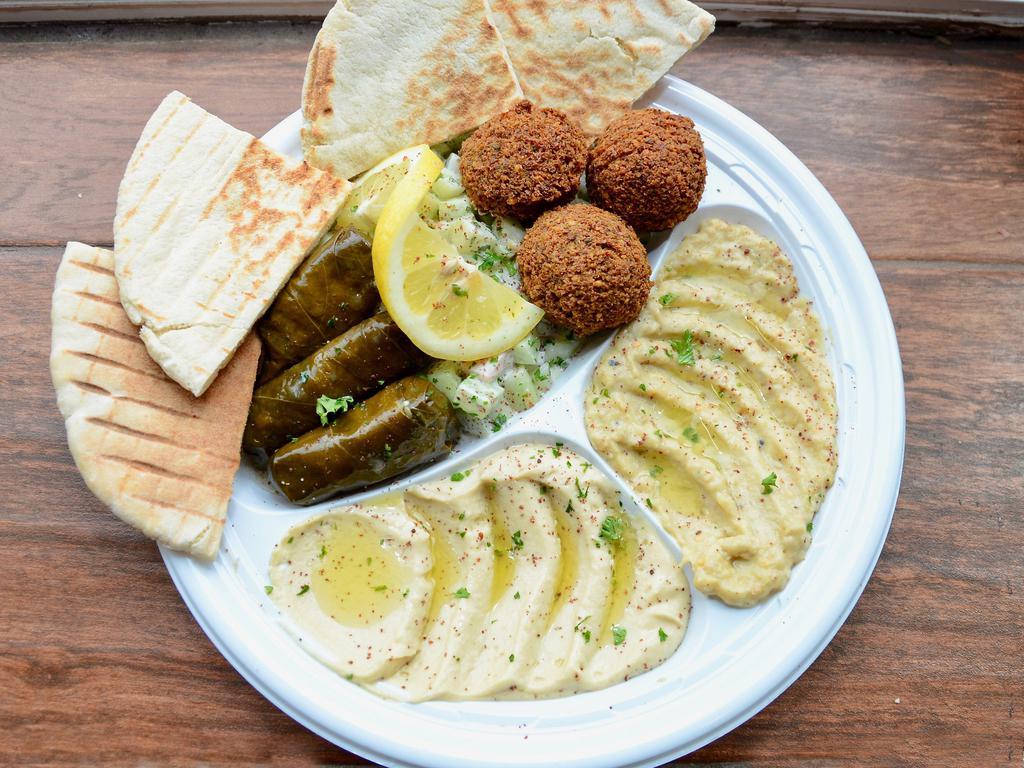 Vegetarian Assrotment · A combination plate of hummus, baba ghanouj, dolmas, falafels, and choice of salad, served with a side of tahini sauce and grilled pita. Vegan.