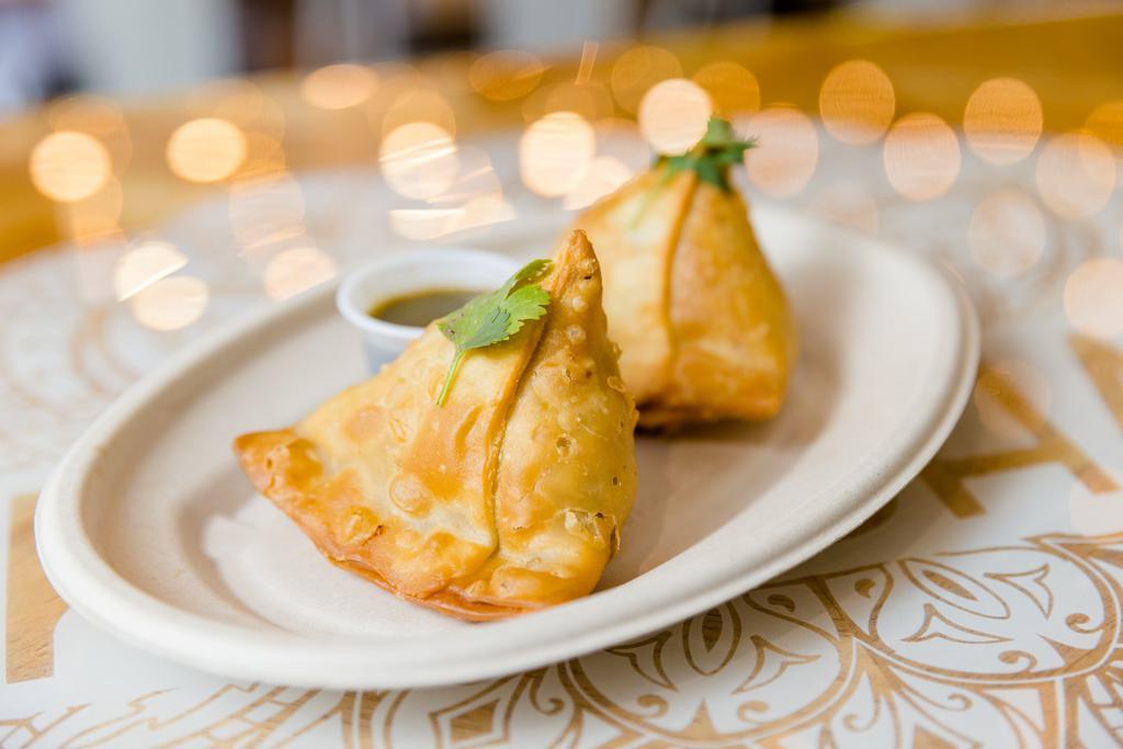 Samosas · Two crispy pastries stuffed with potatoes, peas, and secret spices.  
Served with a tamarind + chutney.