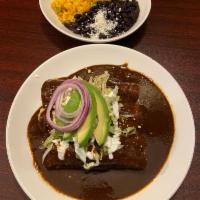 Enchiladas de Mole · 3 rolled corn tortillas in a mole poblano sauce with shredded chicken. Topped with Mexican c...