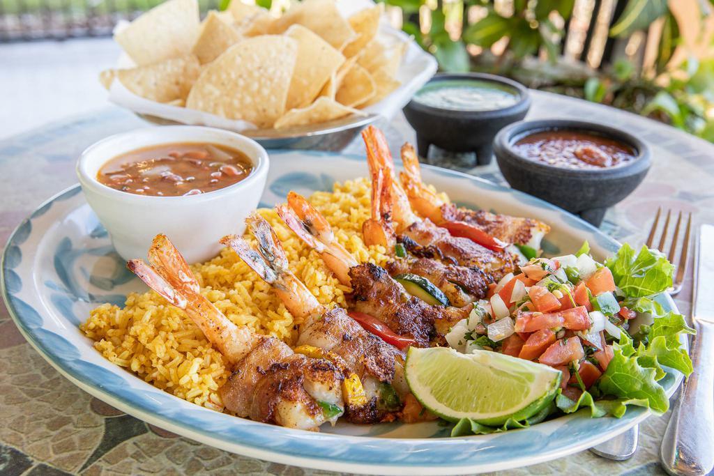 Shrimp Brochette · 6 pieces jumbo shrimp, stuffed with a slice of jalapeno and cheese, wrapped in bacon and grilled. Served with pico de gallo, garlic butter, and your choice of rice and beans.