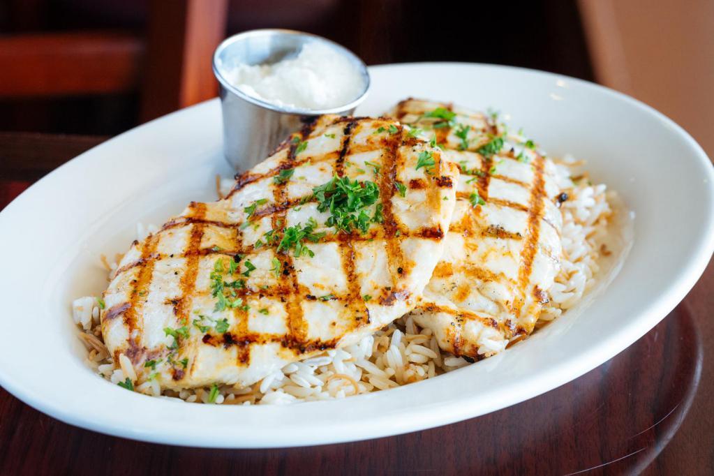 Dajaj Mishiwi · whole breast of chicken, charbroiled and served over rice pilaf with a side of garlic purée. 
