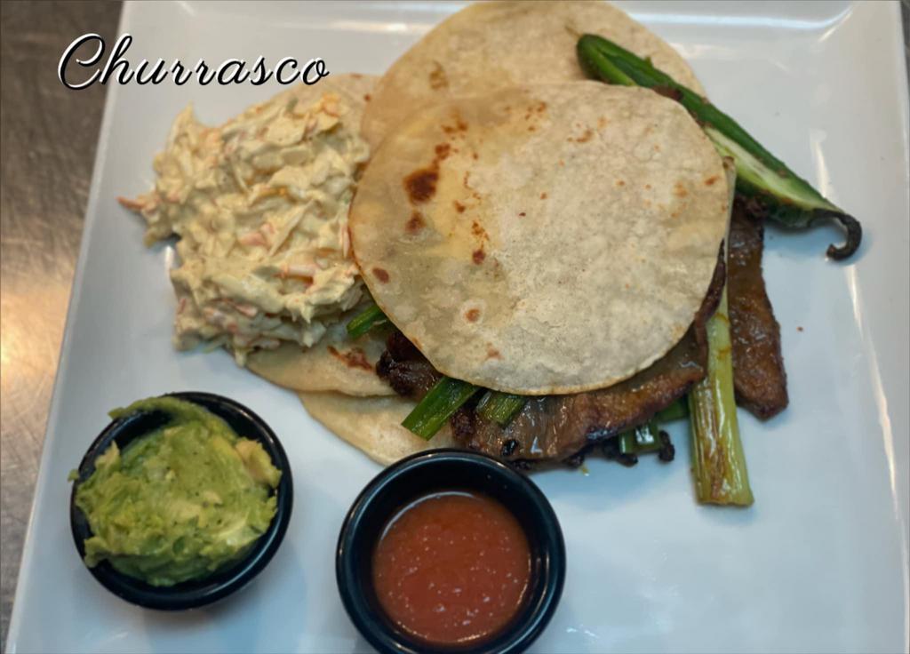 Churrasco · 3 tortillas, grilled steak, coleslaw, red sauce, with grilled onions and guacamole.