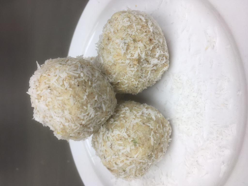 Nariyal Laddu · Creamy blend of Coconut, Almond, Cashew, Pistachio, Poppy Seeds, Cardamom, Cream of Wheat, Pasteurized Cream, Mava, Sugar & shaped into Balls and rolled in Coconut flakes.  (6 pieces)