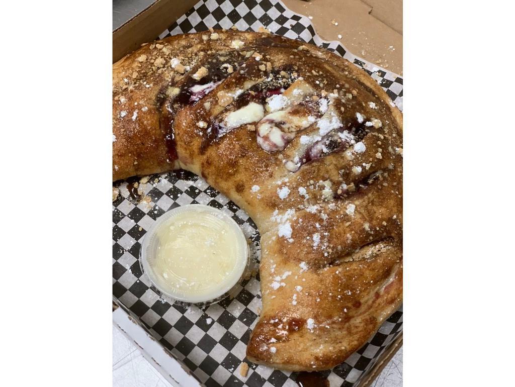 Blueberry Cheescake Calzone · Folded dough filled with cheesecake filling, blueberry pie filling and graham crackers, topped with cinnamon butter and graham cracker crumbles