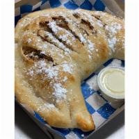 Cheesecake Calzone · Folded dough filled with Cheesecake filling and graham crackers. Topped with cinnamon butter...