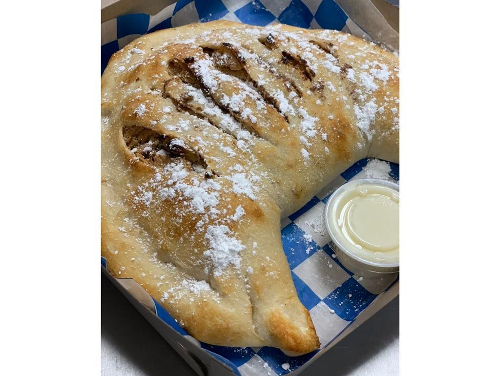 Cheesecake Calzone · Folded dough filled with Cheesecake filling and graham crackers. Topped with cinnamon butter and graham cracker crumbles