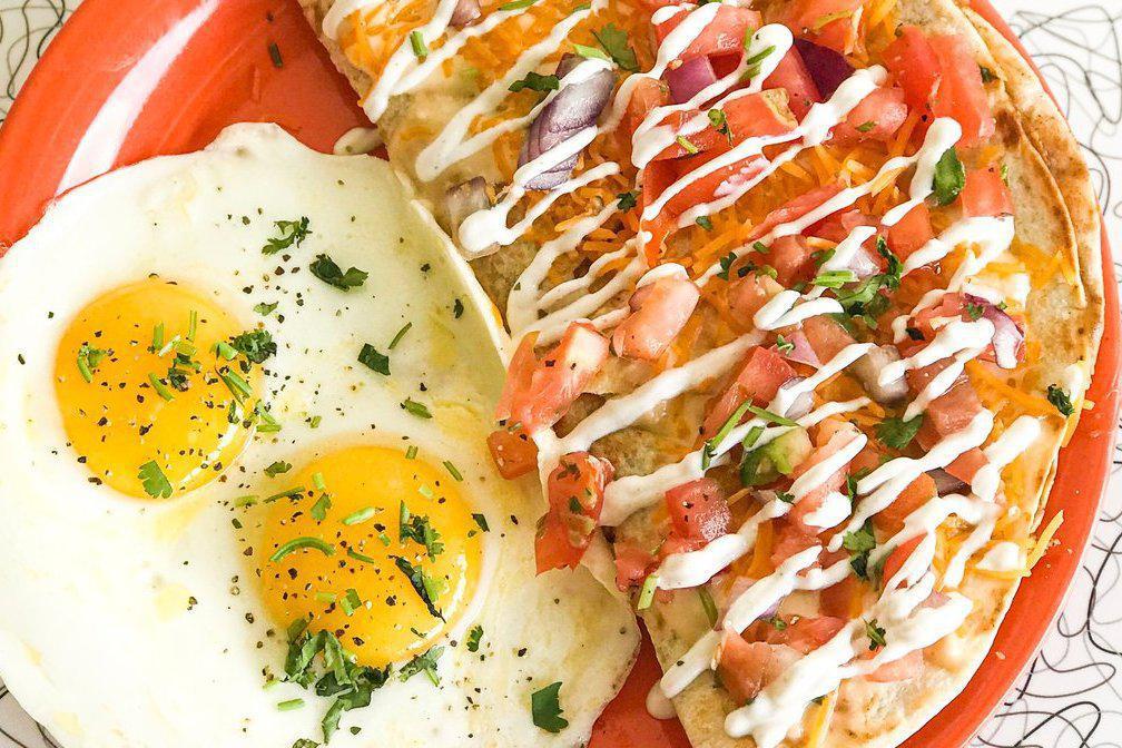 Breakfast Quesadilla Sunny Eggs · Flour tortilla stuffed with blackened chicken, black beans and cheddar cheese. Topped with pico de gallo, cheddar cheese, queso and crema. Served with two sunny side eggs.
