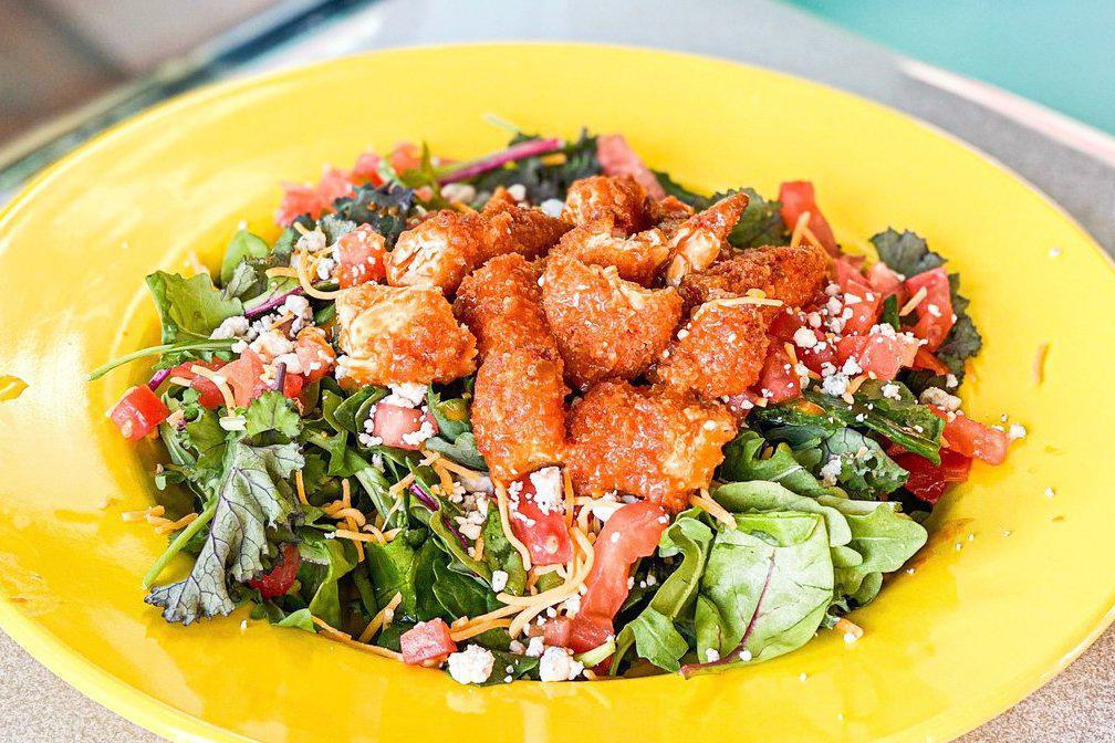 Buffalo Chicken Salad · Deep fried crispy chicken tenders dipped in HOEmade buffalo sauce topped with cheddar cheese, blue cheese crumbles and diced tomatoes on a bed of mixed greens.