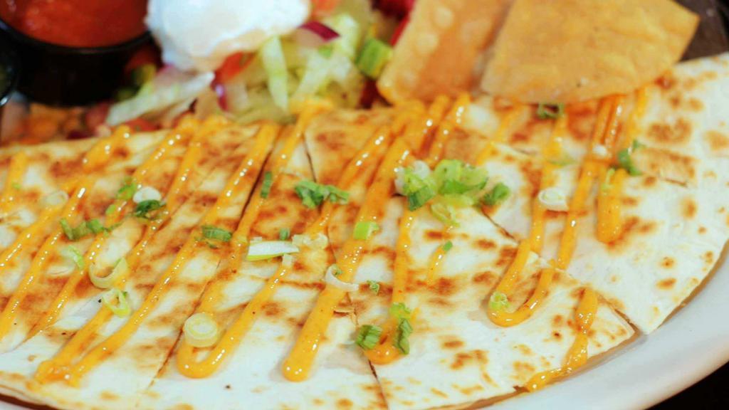 Quesadilla · Grilled flour tortilla stuffed with green chiles and blended cheese drizzled with chipotle mayo.  Served with sour cream and salsa. Add chicken or beef for $2.

